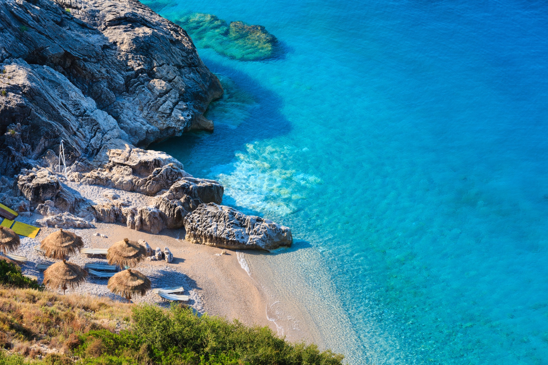 Liten strandvik med kristallklart turkost vatten vid den albanska kusten